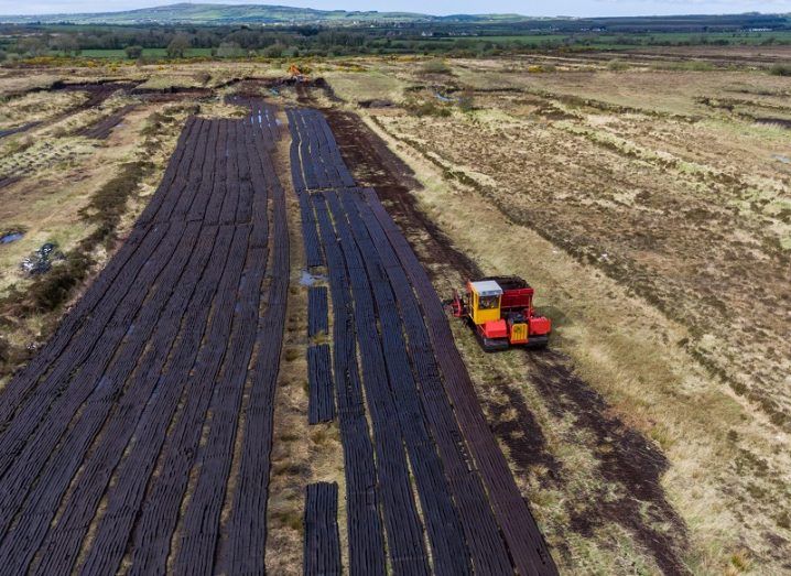 Aerial view of a tractor harvesting peat from a bog in the midlands.